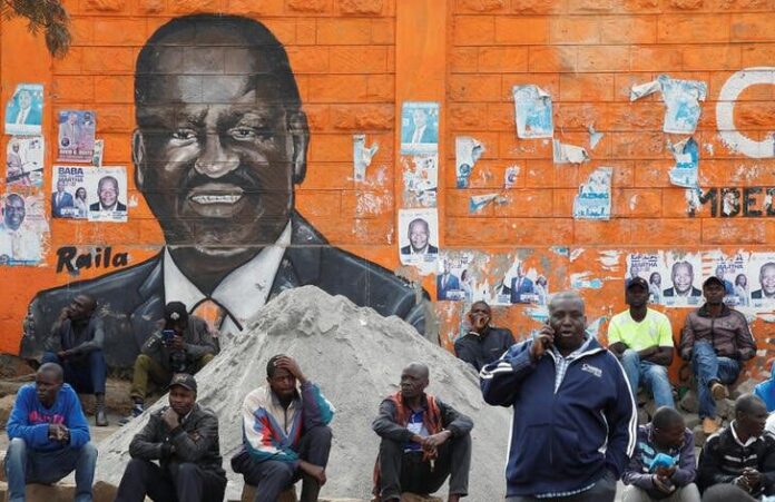 People sit next to a wall mural of Raila Odinga the presidential candidate for Azimio la Umoja and One Kenya Alliance, after the general election conducted by the Independent Electoral and Boundaries Commission (IEBC) in Kibera slums of Nairobi, Kenya August 12, 2022. REUTERS/Monicah Mwangi