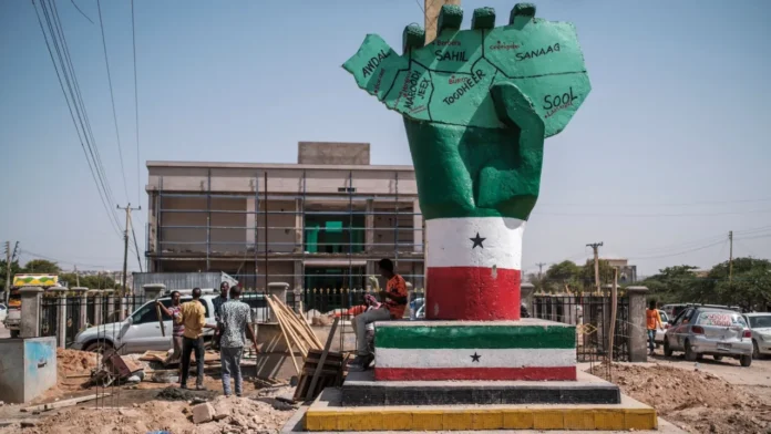People stand next to the Independence Monument, depicting a hand holding a map of the country, in the city of Hargeisa, Somaliland, on September 19, 2021. (Photo by EDUARDO SOTERAS/AFP via Getty Images)